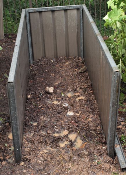 three sides of metal waist high garden bed together on muddy ground